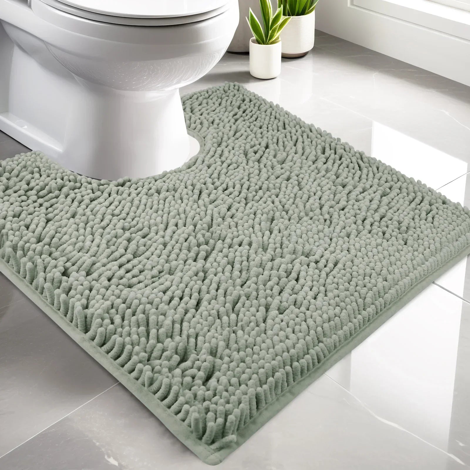 Luxury chenille U-shaped contour bath rug in sage green placed around toilet base in modern white bathroom