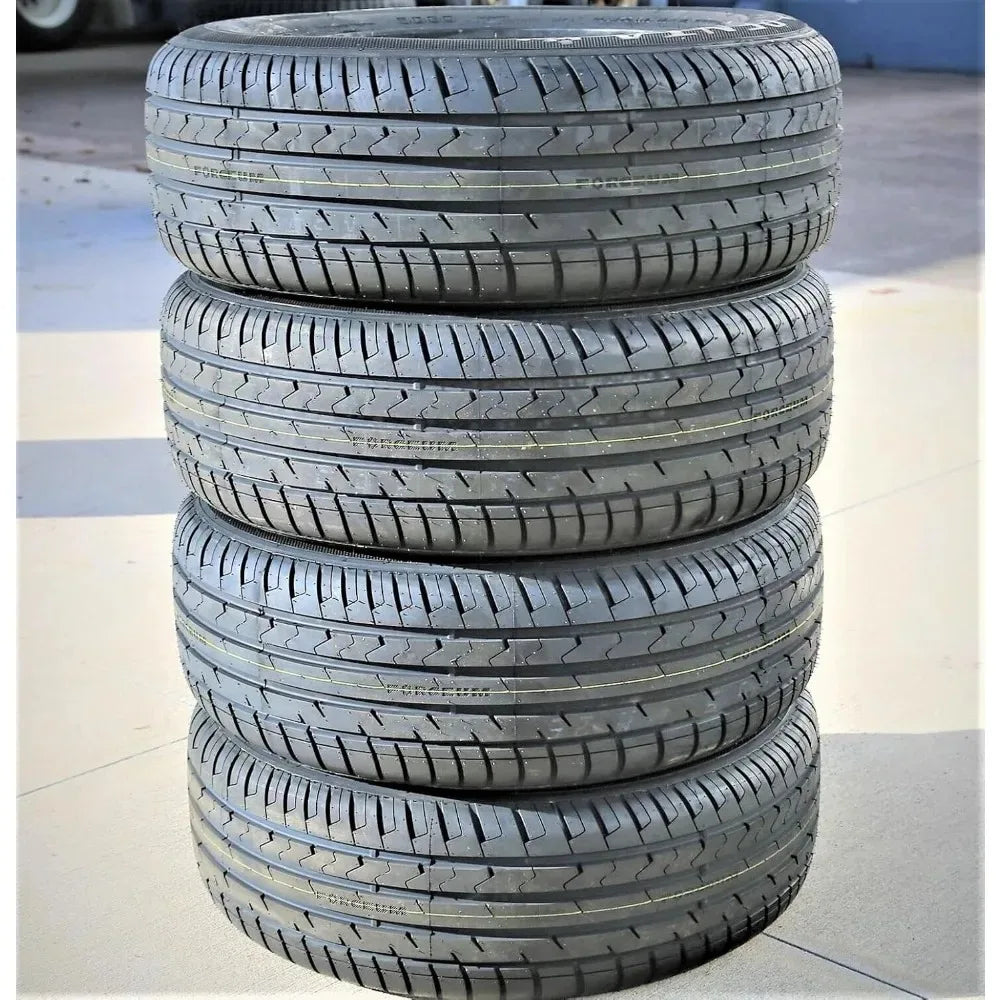 A stack of four black all-weather car tires with visible tread patterns, photographed outdoors on a concrete surface.