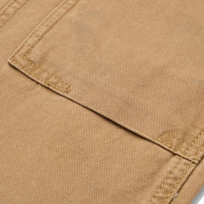 Close-up of a tan canvas fabric surface showing a stitched pocket corner and woven texture.
