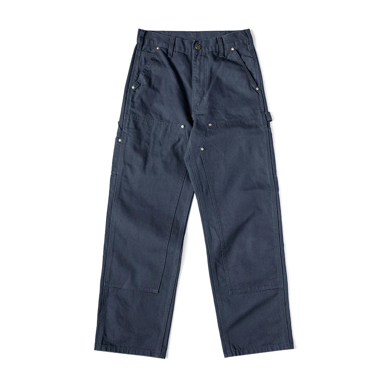 A pair of dark navy blue work pants with multiple utility pockets and brass rivets, laid flat against a white background.