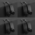 Four identical views of a black leather phone stand with a metal ring at the top and two black rubber feet, arranged in a 2x2 grid on a dark gray background.