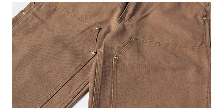 Close-up of brown pants showing the front pocket and side seam details.