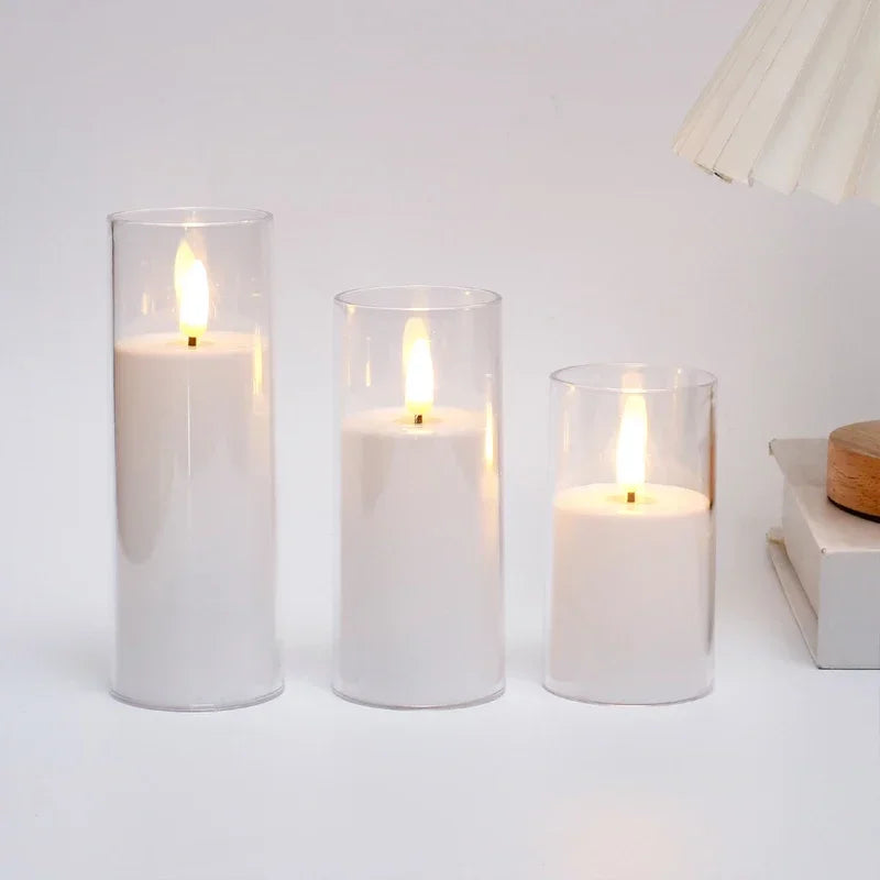 Three white candles in glass holders on a white surface with a neutral background