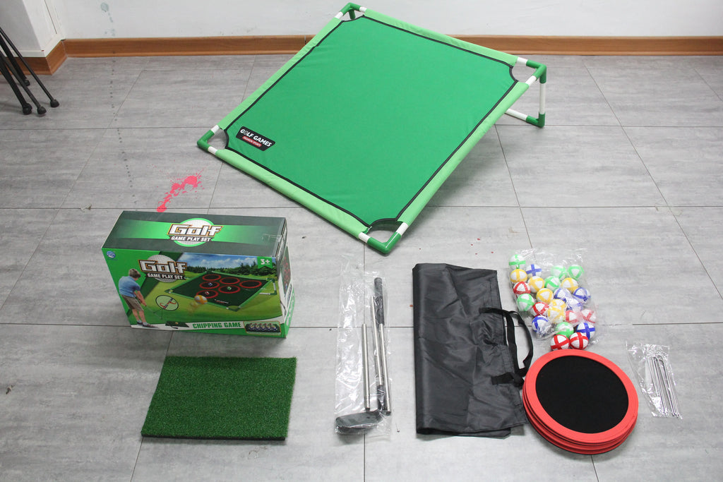 A green mini billiards table set laid out on a gray tiled floor, including the folded table, product box, turf mat, bags, mallets, and colorful balls.