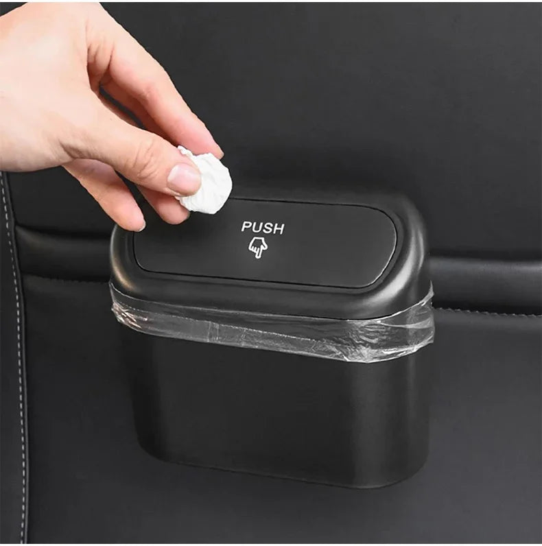 Black car trash can with push lid on a black car seat.
