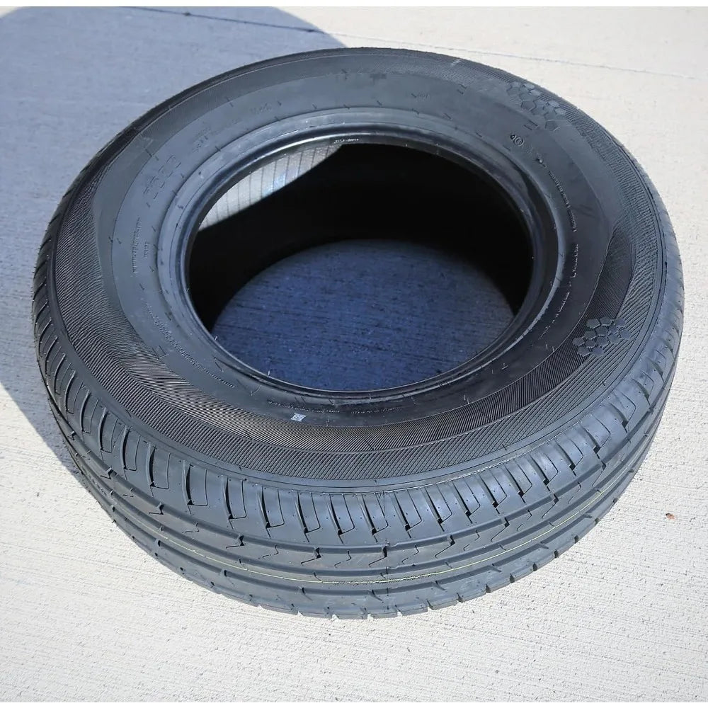A single black rubber tire photographed outdoors on a light concrete surface, with no person or animal present.