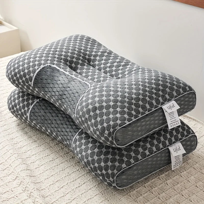 Two gray patterned pillows stacked on a textured surface with a white wall in the background.