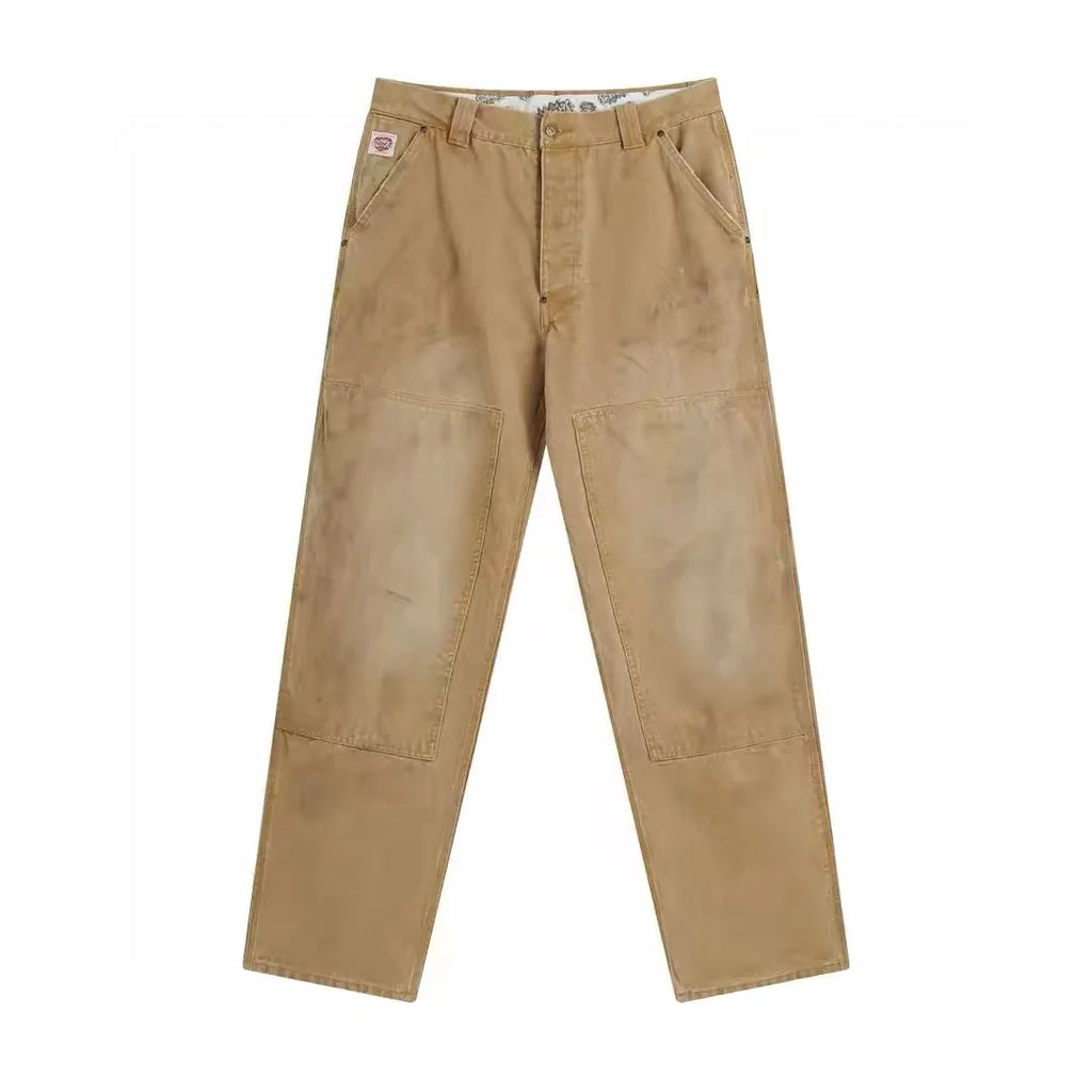 A pair of tan work pants with large reinforced knee patches, shown flat against a plain white background.