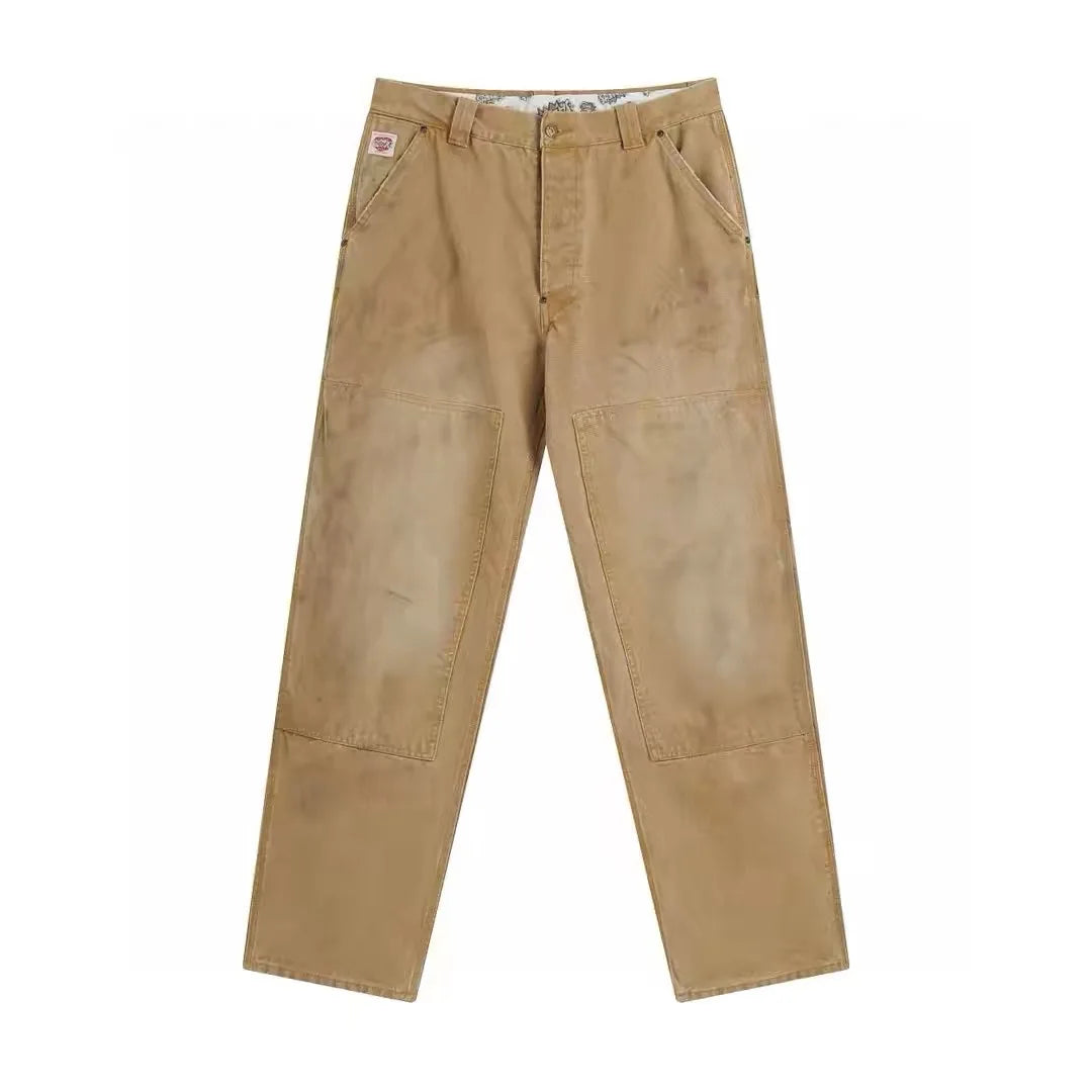 A pair of tan work pants with large reinforced knee patches, shown flat against a plain white background.