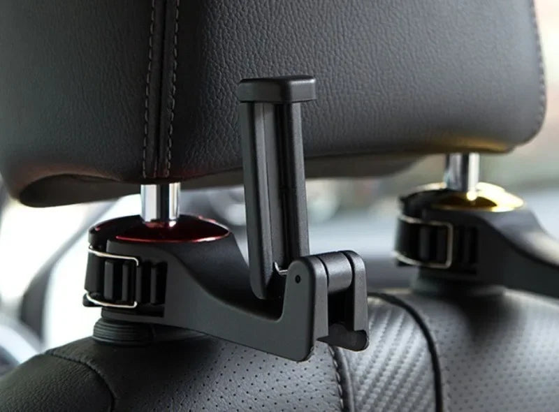A black plastic car headrest accessory mounted onto a car seat headrest, shown in a close-up shot.