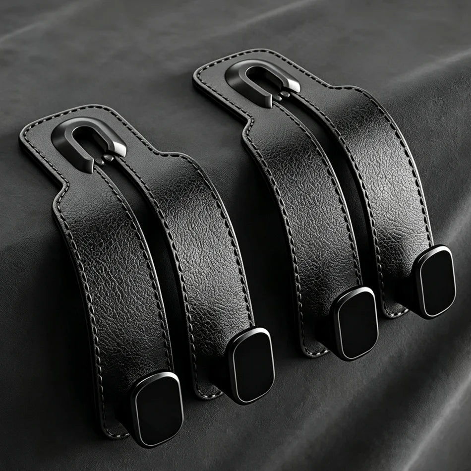 Two black leather strap accessories with metal clips and black rubber pads, arranged on a dark textured fabric background.