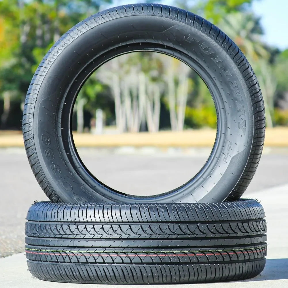 Two tires stacked on a concrete surface with a blurred green outdoor background