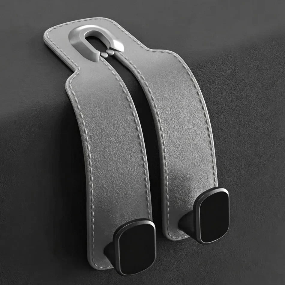 A pair of gray faux-leather car seat belt covers with black plastic anchors, shown on a dark gray background.