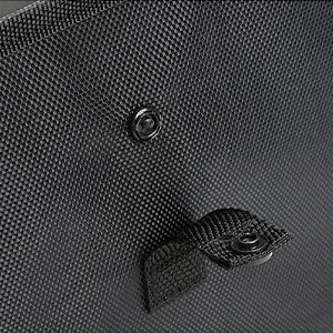 Close-up of a black textured fabric surface with a snap button and a small black strap or tab attached.