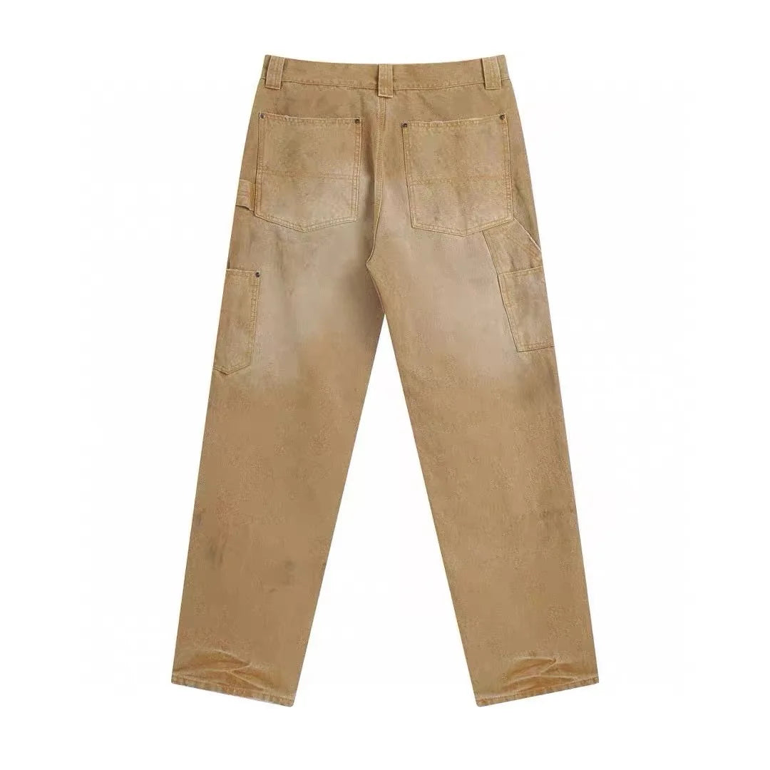 A pair of light brown or tan work pants shown from the back, featuring a button closure, belt loops, two large back patch pockets, and two side cargo pockets, laid flat against a white background.