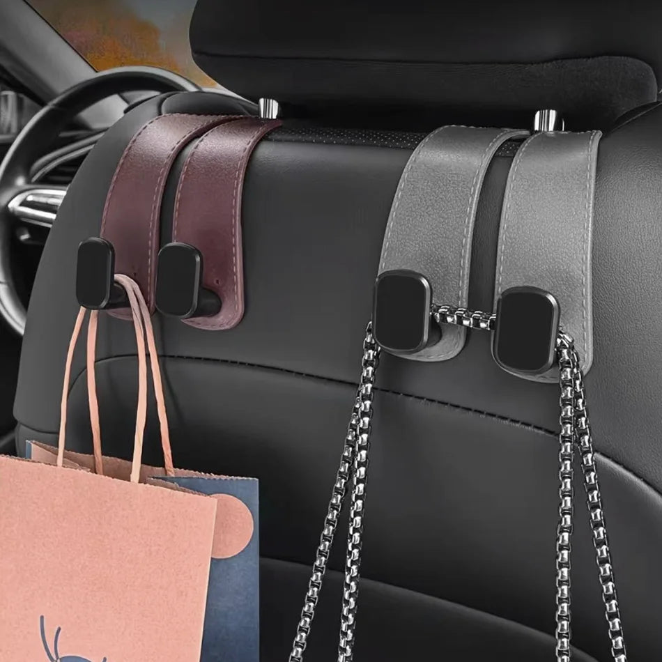 Two car seat backrest organizer clips attached to a black car seat, holding a pink shopping bag and a silver chain bag.