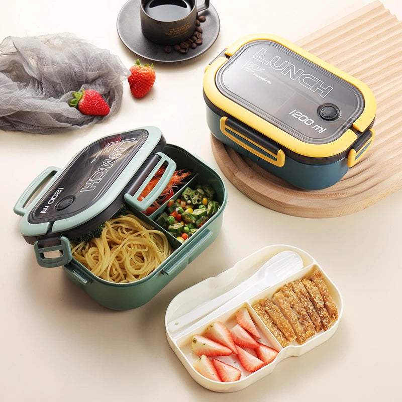 Three insulated lunch containers arranged on a light beige surface with food trays and strawberries. The containers are shown closed and open, with one in dark green, one in yellow and dark blue, and one in mint green and dark blue.