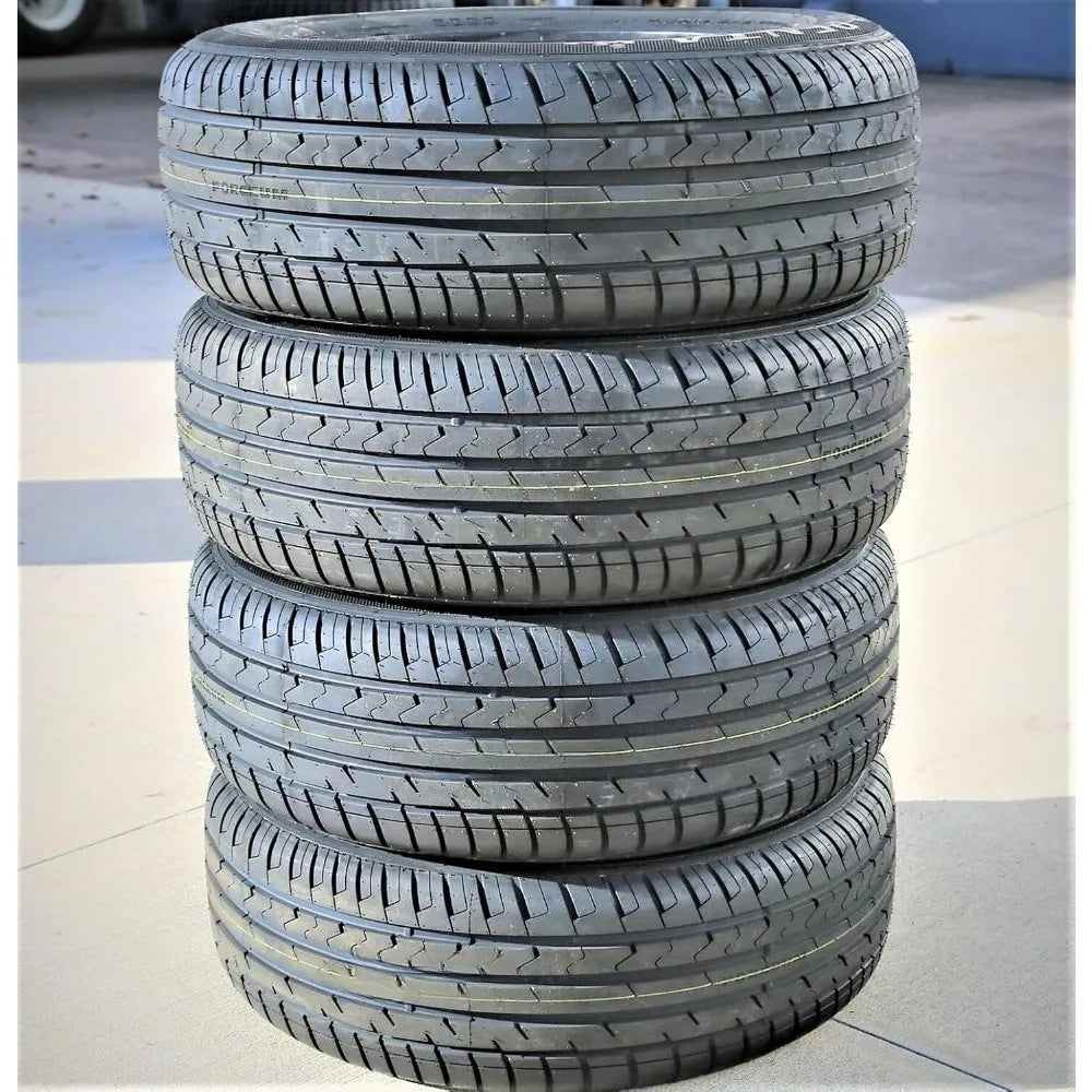 Four stacked black car tires showing their tread patterns, photographed outdoors on a concrete surface.