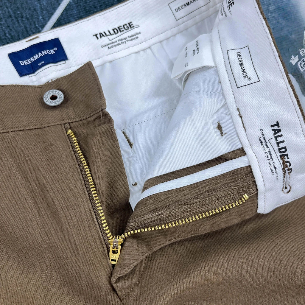 Close-up of a pair of brown chino pants showing the inner waistband, white lining, zipper, and Dreesmann brand labels.