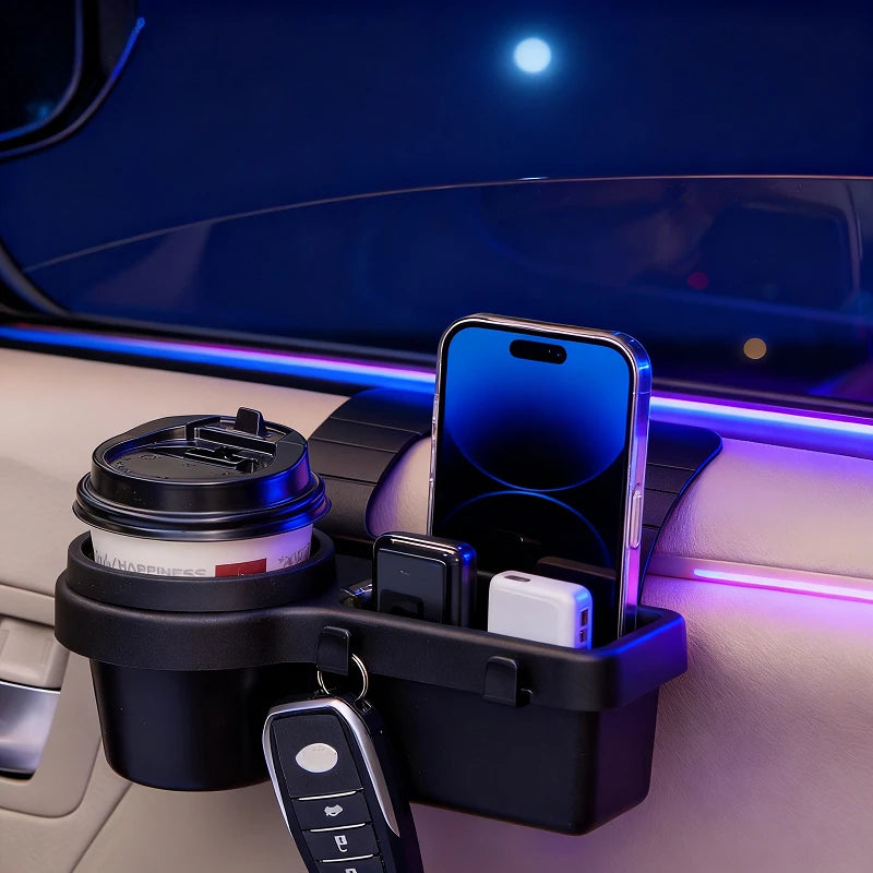 A black car dashboard organizer mounted on a car air vent, holding a coffee cup, a smartphone, a key fob, and small accessories. The scene is lit with blue and purple ambient car lighting.