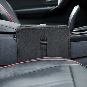 A black textured car seat organizer pouch mounted on a black leather car seat with red contrast stitching.