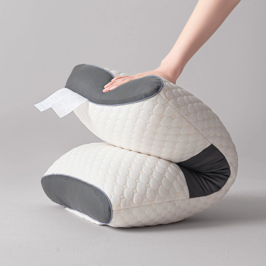 White and gray ergonomic pillow with a hand touching it on a gray background