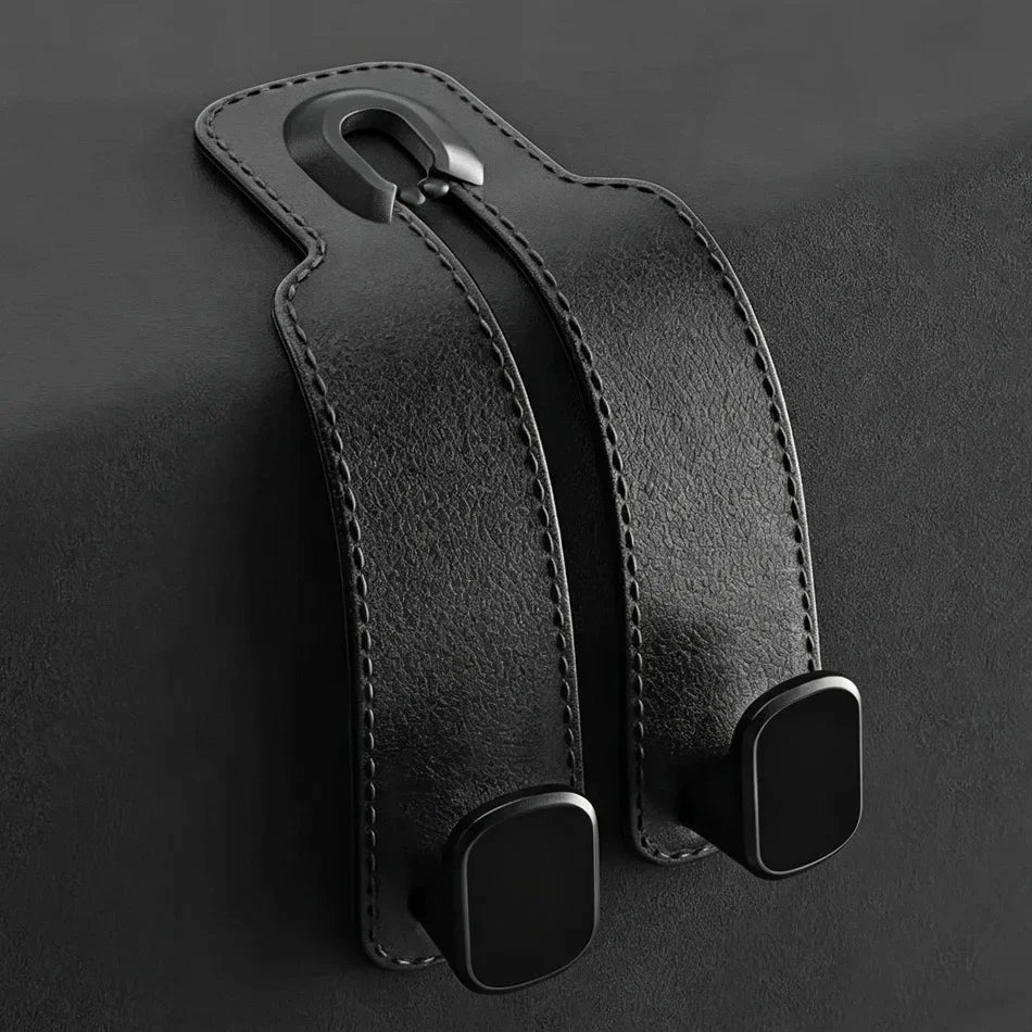 Black leather car seat belt clip with a metal D-ring and two mounting clips, shown on a dark textured background.