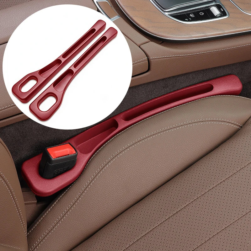 A red plastic car seatbelt release latch cover shown installed on a brown leather car seat, with a circular inset showing the two latch components separately.