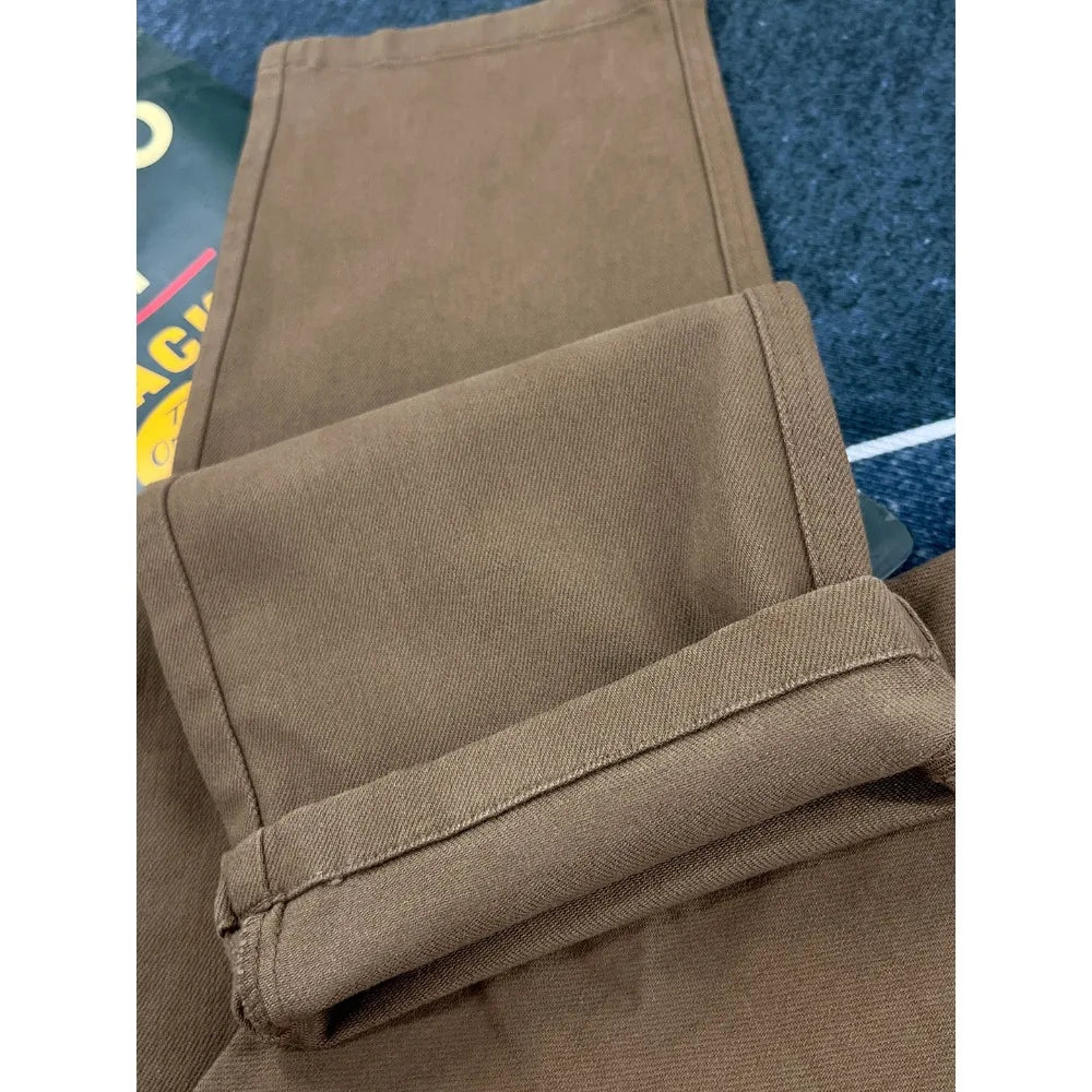 A close-up of folded brown pants showing the fabric texture and stitching, placed on a dark blue textured surface.
