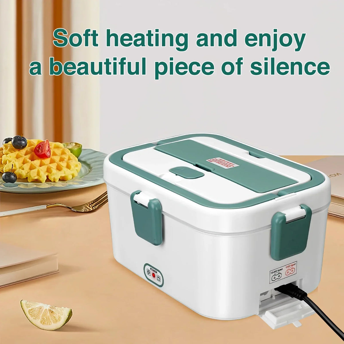 White and green electric lunch box on a table with waffles and a book in the background.