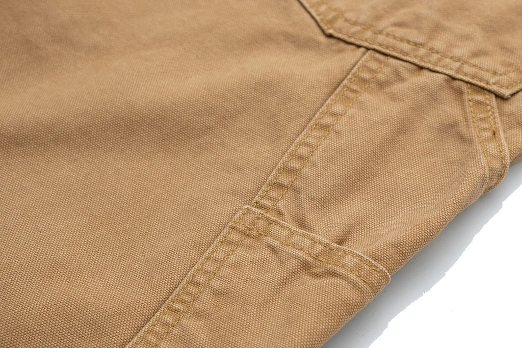 Close-up of tan canvas fabric with a diagonal pocket seam on a white background.